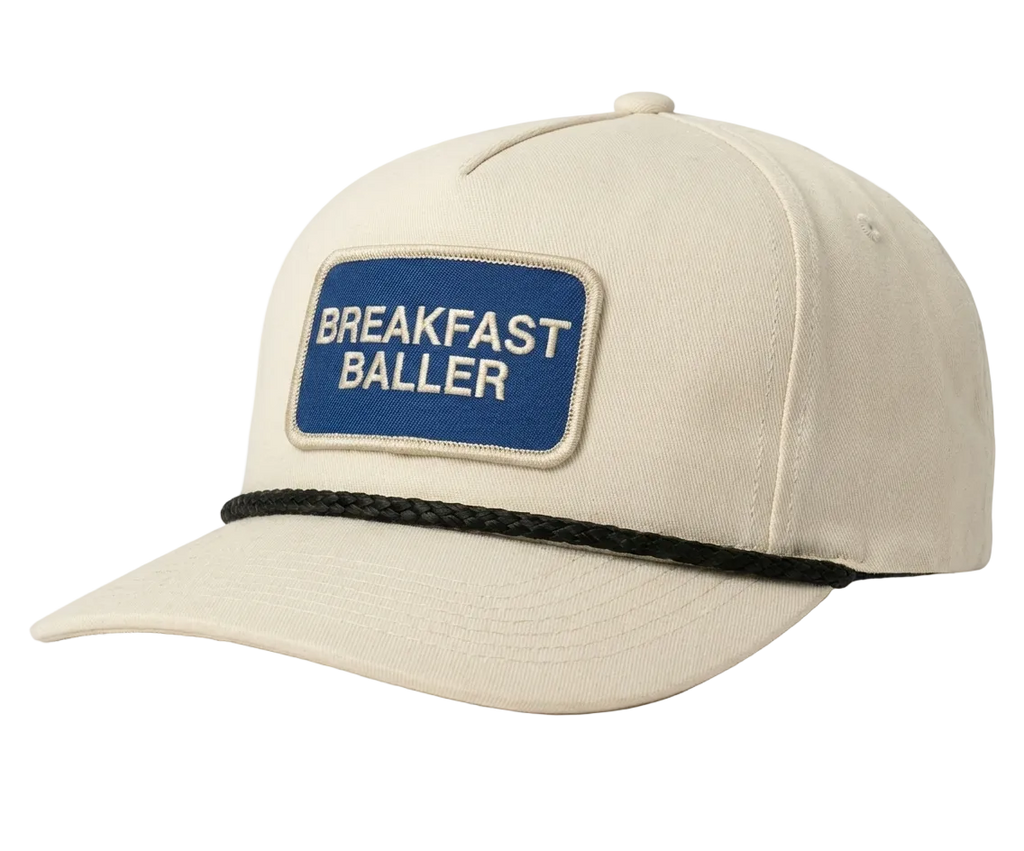 Beige cap with a blue patch displaying 'Breakfast Baller' on a white background